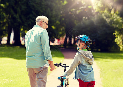 家庭,世代,安全人的快乐的祖父男孩,自行车自行车头盔夏季公园交谈祖父男孩夏季公园骑自行车图片