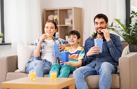 家庭休闲人的快乐的母亲父亲儿子家吃爆米花看电视家里爆米花看电视的幸福家庭图片