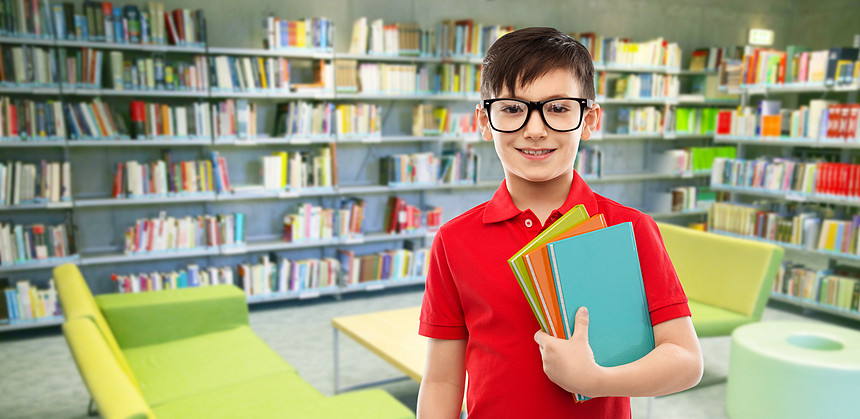 学校,教育人的微笑的小学生男孩穿着红色马球T恤,戴着眼镜,书图书馆背景的阅览室里图书馆戴眼镜带书的小学生图片