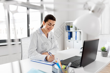 医学,医疗职业微笑的女医生穿着白色外套,带笔记本电脑医疗报告医院带笔记本电脑的医生医院的医疗报告图片