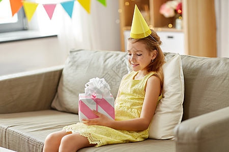 童庆祝快乐的女孩家里的生日聚会上带着礼品盒快乐的女孩戴着派帽,家里生日礼物图片