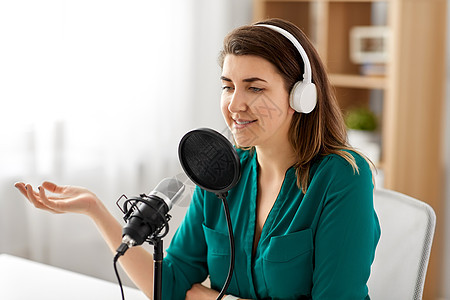 技术,大众媒体人的妇女与麦克风耳机交谈录音播客演播室演播室里麦克风录音播客的女人图片