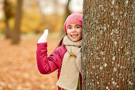童,季节人的快乐的女孩秋天的公园里偷看树快乐的女孩秋天的公园里偷看树图片
