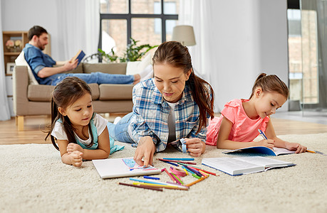 家庭,母亲休闲的母亲花时间她的小女儿画画,并帮助家庭作业躺家里的地板上母亲花时间小女儿家里图片