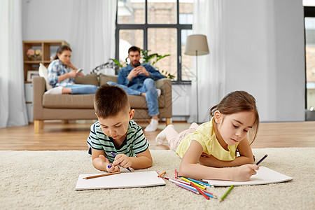 家庭休闲人的兄弟姐妹躺地板上,家用蜡笔素描簿上画画哥哥妹妹家用蜡笔画画图片