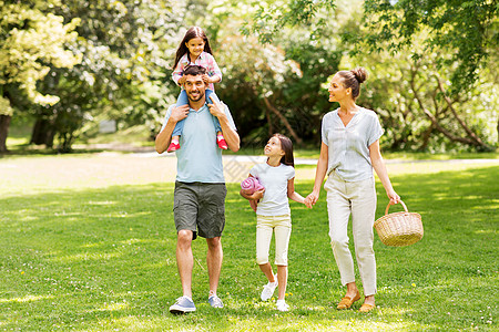家庭休闲人的快乐的母亲带着野餐篮,父亲两个女儿夏季公园散步家人带着野餐篮夏天的公园散步背景图片