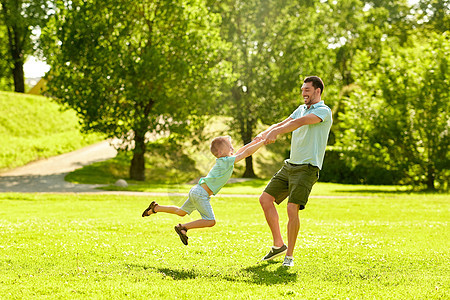 家庭,休闲人的快乐的父亲小儿子夏季公园玩得开心快乐的父子夏天的公园玩得开心图片