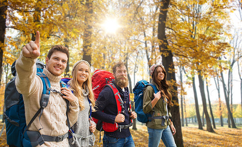 旅行,旅游徒步旅行的群微笑的朋友带着背包秋天的公园背景下散步朋友们带着背包秋天徒步旅行图片
