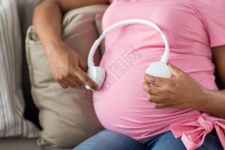 怀孕,技术人的接近怀孕的非裔美国妇女,戴着耳机她的肚子家里孕妇肚子上戴着耳机图片