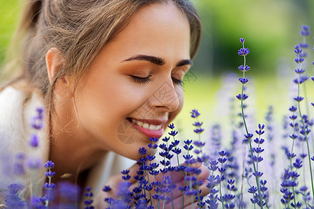 园艺人们的夏季花园里,快乐的轻女人闻着薰衣草的花靠近闻着薰衣草花的女人图片