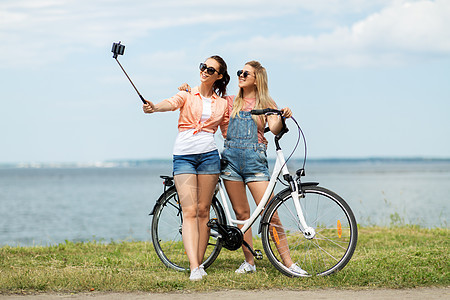休闲,技术友谊的快乐微笑的十几岁女孩朋友骑自行车拍照智能手机海边夏天夏天自行车自拍的十几岁女孩图片