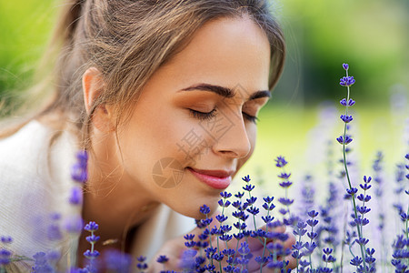 园艺人们的夏季花园里,快乐的轻女人闻着薰衣草的花靠近闻着薰衣草花的女人图片