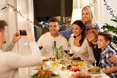 庆祝,假日人们的快乐的家庭家里举行晚餐聚会,并智能手机自拍家人举行晚宴自拍图片