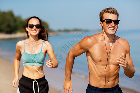 健身,运动技术快乐的夫妇与耳机运行夏季海滩夫妇带着耳机海滩上跑来跑背景图片