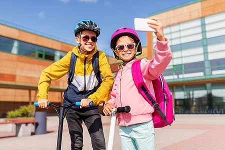 户外用智能手机自拍快乐的学校孩子与滑板车自拍图片