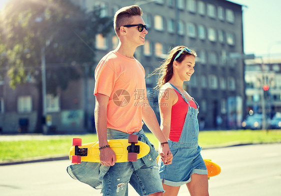 暑假,极限运动人们的快乐的青少夫妇与短现代巡洋舰滑板沿着城市街道行走轻夫妇城市街道上滑板图片