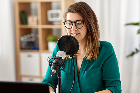 技术,大众媒体人们的戴着麦克风笔记本电脑的眼镜的女人录音室交谈录制播客演播室里麦克风录音播客的女人图片