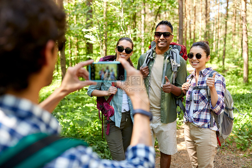 旅行,旅游徒步旅行群朋友与背包被智能手机拍摄森林带背包的朋友徒步旅行中被拍照图片