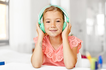 音乐耳机儿童技术快乐的女孩耳机听音乐家里的桌子戴耳机的女孩家听音乐背景