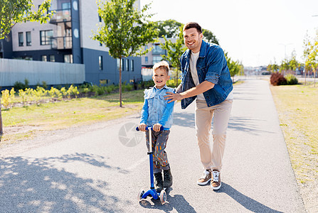 家庭,休闲父亲的快乐的父亲花时间小儿子骑滑板车城市快乐的父亲小儿子城市骑滑板车图片