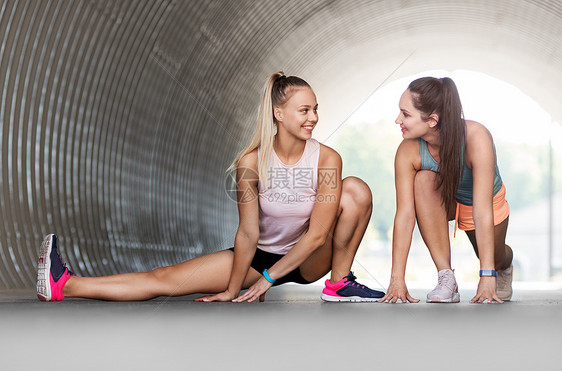 健身,运动健康的生活方式微笑的轻妇女女朋友与活动跟踪者伸展户外健身追踪器的女人户外伸展图片