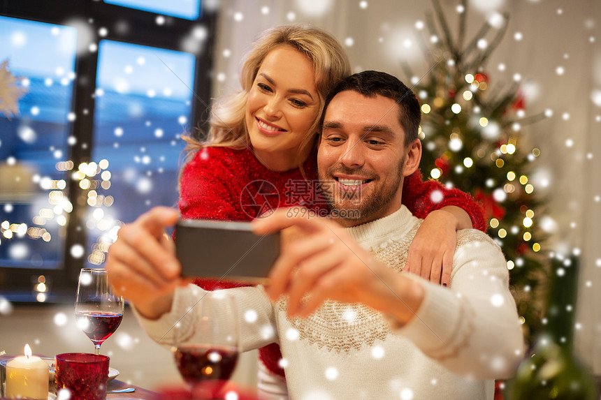 诞节,假日,技术人的快乐的夫妇雪地上的家庭晚餐上用智能手机自拍快乐的夫妇诞晚餐上自拍图片