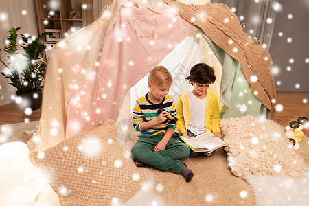 童,诞节友谊的快乐的男孩阅读书与火炬灯孩子帐篷帐篷家里的雪快乐的男孩家孩子们的帐篷里看书图片