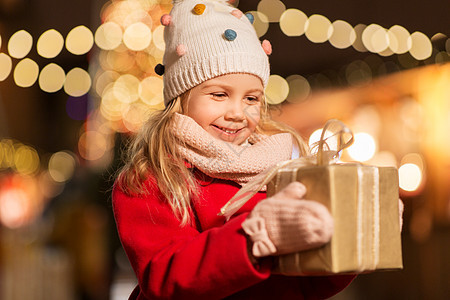 假期,童人的快乐的小女孩与礼品盒诞节市场冬季晚上诞市场上带礼品盒的快乐女孩背景图片