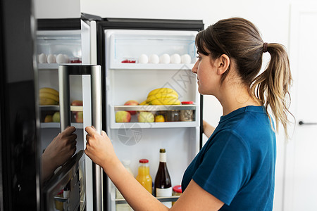 女人打开厨房里的冰箱图片