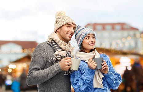 人们寒假的幸福的浪漫夫妇戴着针帽围巾,塔林市背景的老城诞市场上戴着杯子幸福的夫妇诞市场喝咖啡图片