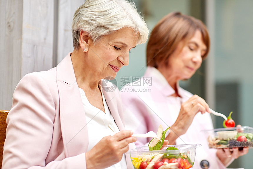 老休闲食物老妇女朋友城市街道上吃外卖沙拉城市街道上吃外卖食物的老年女子图片