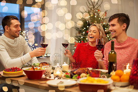 节日庆祝快乐的朋友家里吃诞晚餐喝红酒快乐的朋友诞节聚会上喝红酒图片