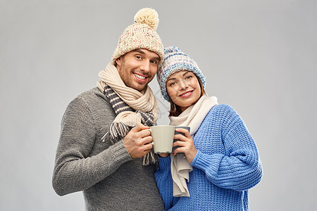 人们,诞节爱的幸福的浪漫夫妇戴着针帽围巾,背景灰色的杯子穿着冬天衣服杯子的幸福夫妇图片