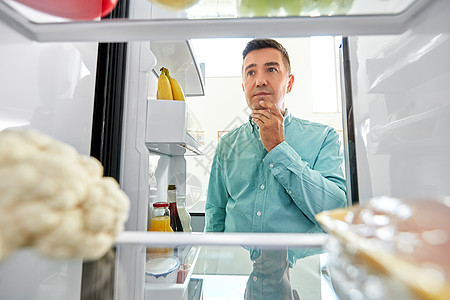 饮食饮食微笑的中男子厨房冰箱里寻找食物厨房冰箱里找食物的人图片