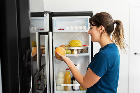 快乐的女人看着冰箱里的柚子图片