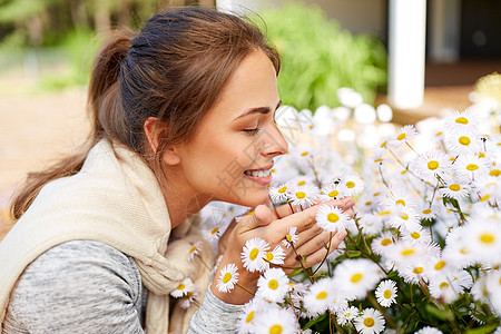 快乐的女人闻着花园里的洋甘菊花图片
