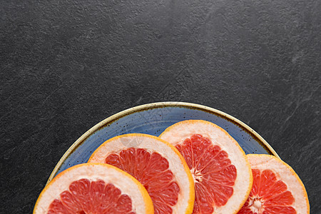 背景上的盘子把新鲜多汁的葡萄柚放盘子里图片