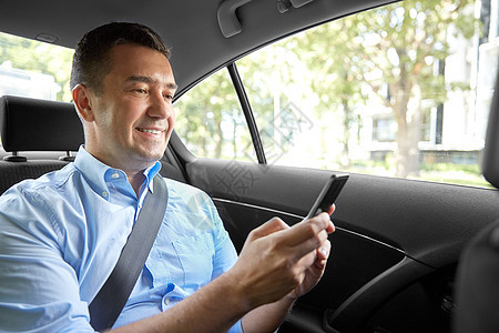 运输商业通信微笑的男乘客商人用智能手机出租车后座乘客商人汽车中用智能手机图片
