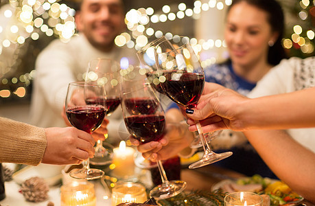 节日庆祝亲密的快乐朋友家里吃诞晚餐,喝红酒碰杯亲密的朋友用葡萄酒庆祝诞节背景图片
