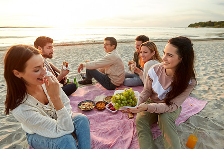 友谊休闲快餐群快乐的朋友夏天海滩野餐时吃三明治汉堡快乐的朋友海滩野餐时吃三明治图片