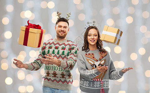 人节日的幸福夫妇的肖像与诞礼物毛衣节日灯背景诞毛衣礼品盒的幸福夫妇图片