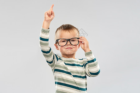 学校,教育视觉微笑的小男孩戴着眼镜,手指指向灰色背景戴眼镜的男孩手指肖像图片