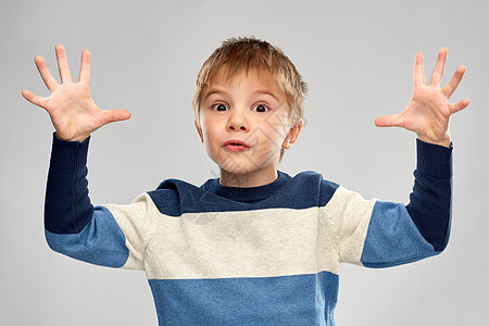 童,表情人的小男孩灰色背景上玩条纹套头衫的肖像穿着条纹套衫玩耍的小男孩的肖像图片
