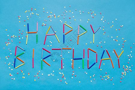 节日,庆祝派单词生日快乐,由彩色蜡烛星形糖洒蓝色背景上用蓝色蜡烛的生日快乐的话背景图片