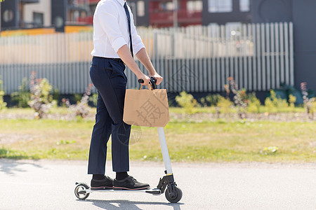 商业人轻商人与外卖纸袋骑电动滑板车户外商人带着外卖纸袋骑滑板车图片