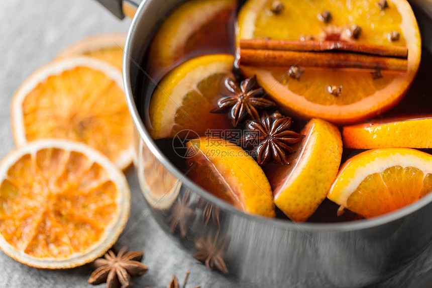 诞节季节饮料锅与热覆盖葡萄酒,橙色切片芳香香料灰色背景锅里热覆盖的葡萄酒橘子片香料图片