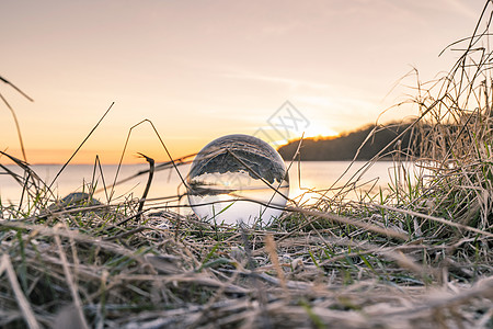 水圆水晶球寒冷的天,清晨日出的湖边,冰封的草地上背景