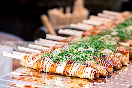 日本京都市西木市场,木棍上酱油蛋黄酱,葱京都的Nishiki市场,木棍上放着酱油蛋黄酱,放着洋葱图片