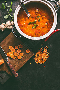 烹饪锅与美味的扁豆汤勺子黑暗的乡村厨房桌子背景与配料,顶部视图与健康素食食品图片