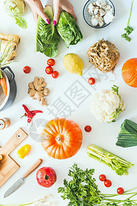 用南瓜各种季节蔬菜锅砧板刀白色桌子背景上着生菜的女手收获烹饪平躺健康的生活方式饮食低碳水化合物图片
